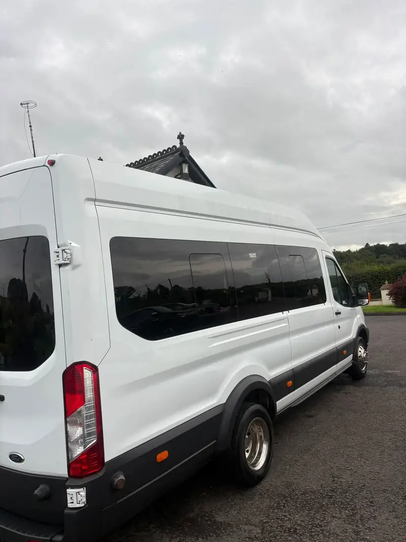 Side of the white minibus showing the long run of tinted passenger windows